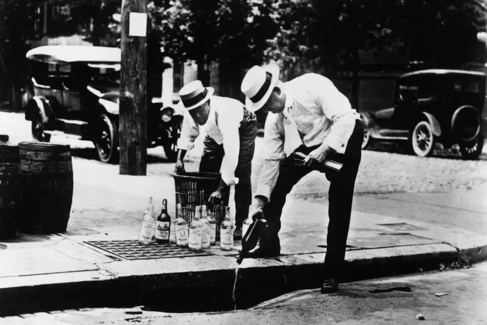 Two men pouring alcohol down a drain during prohibition, 1920. (Getty)